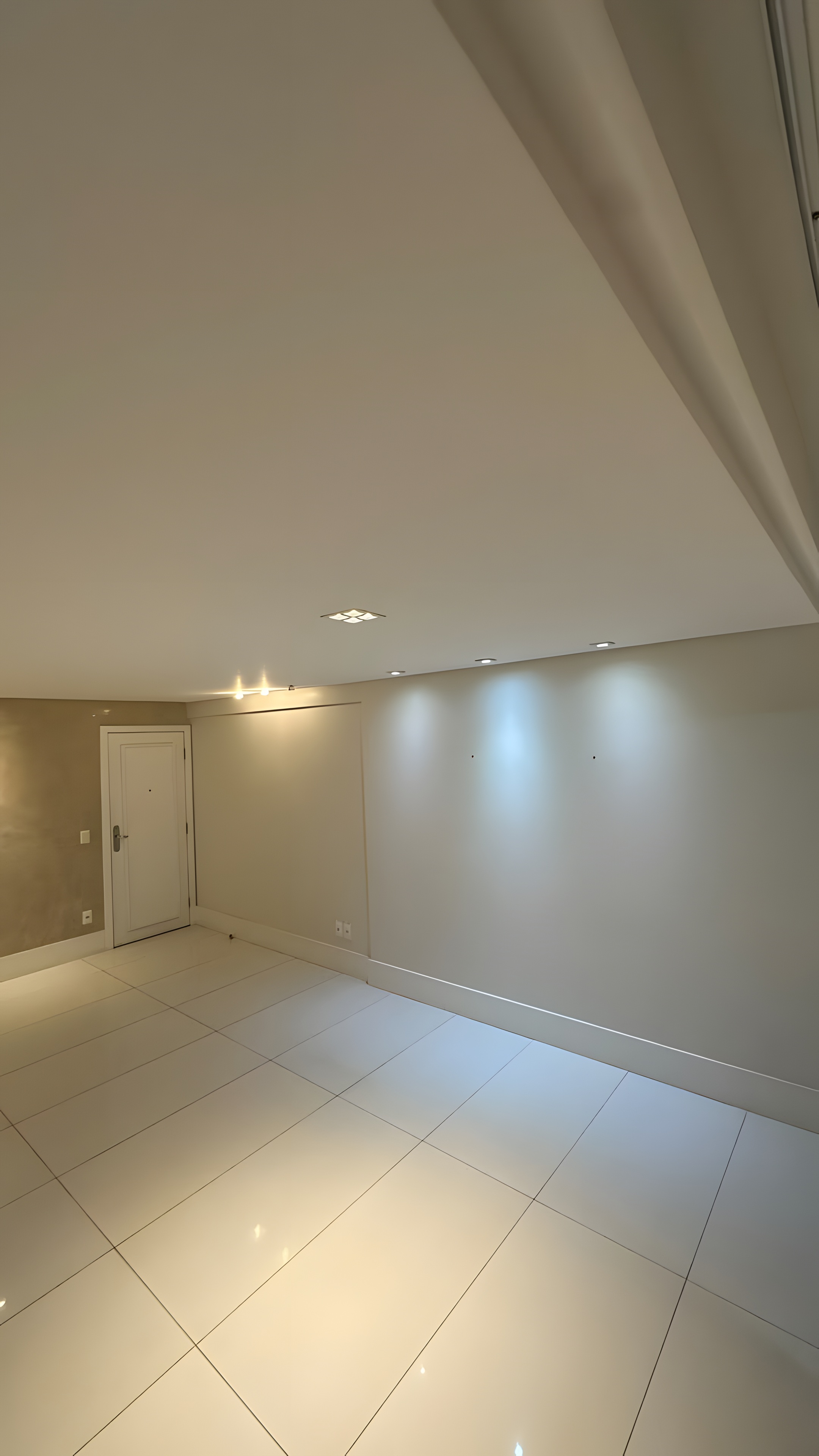 Sala vazia com spots embutidos e porta ao fundo
